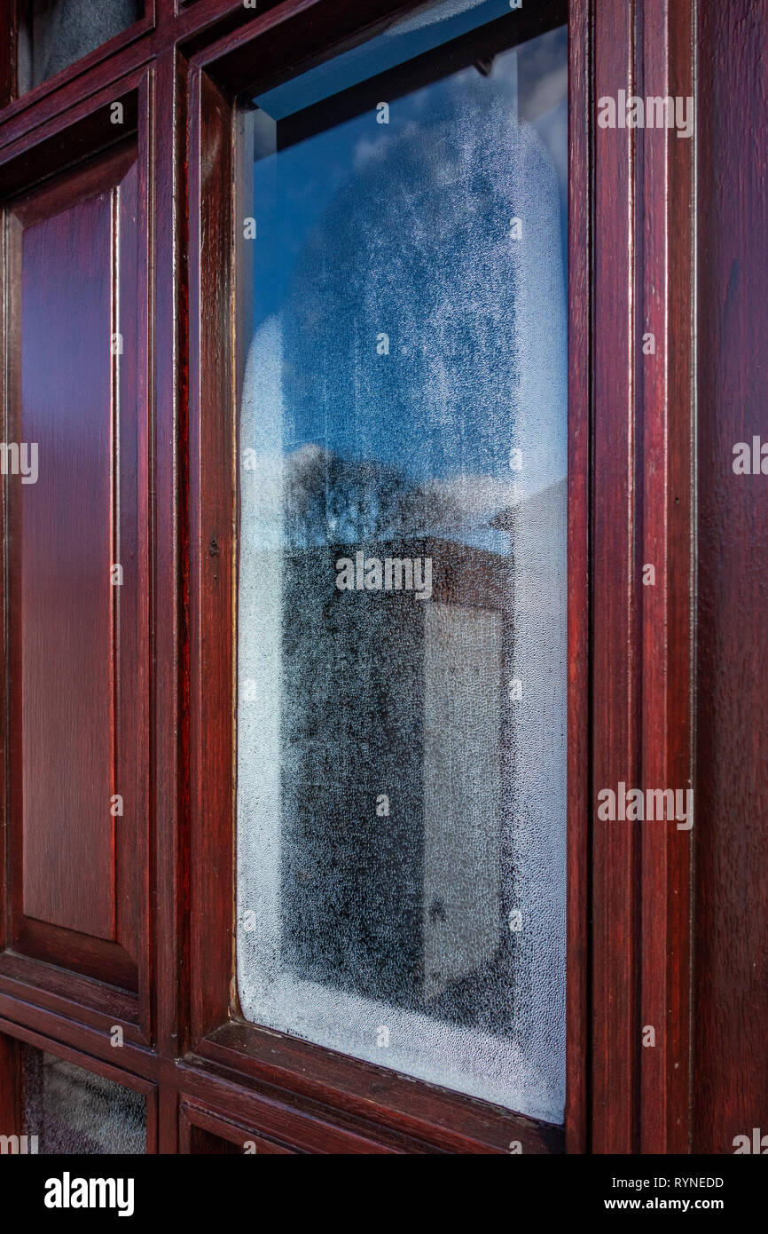 Single glazed door window with condensation forming on the inside of