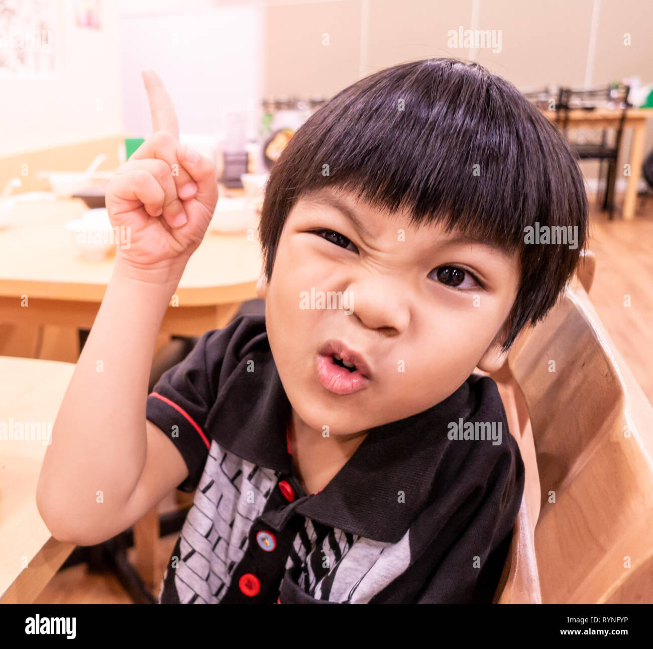 Hungry Funny child posing angry waiting for food in restaurant. Stock Photo
