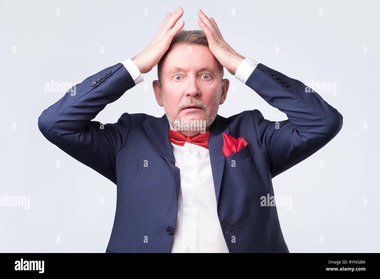 Senior angry man with hand at head on studio wall Stock Photo