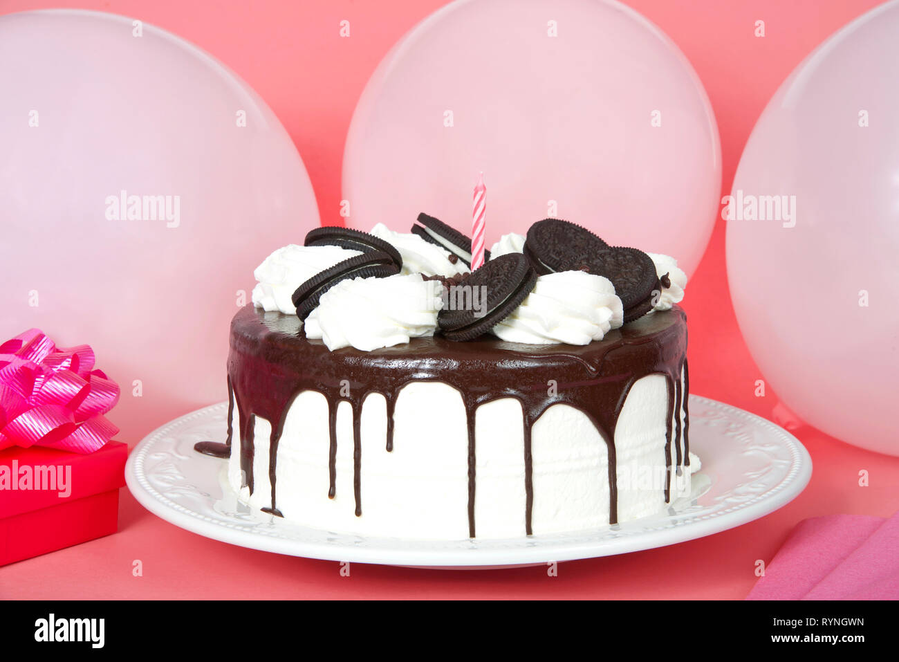 White whipped cream frosted cake with chocolate cream filled sandwich wafer cookies, melted chocolate melting down the sides on a porcelain plate, on  Stock Photo