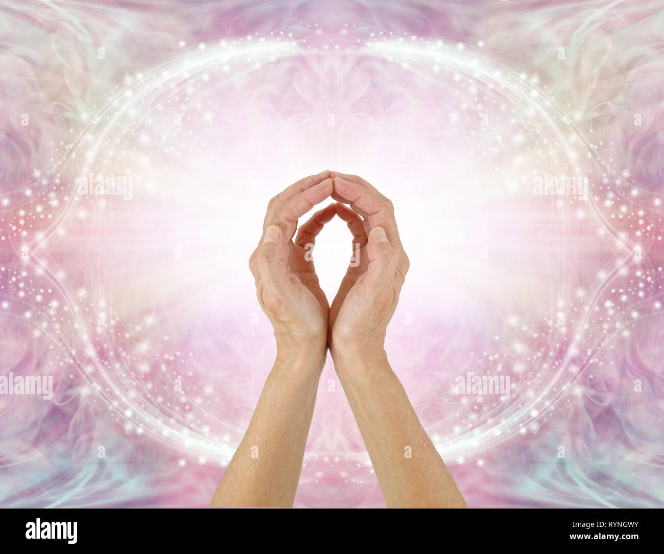 Healer sending Unconditional Love Healing Energy - female hands reaching up making an O shape with a bright white light against sparkling pink frame Stock Photo
