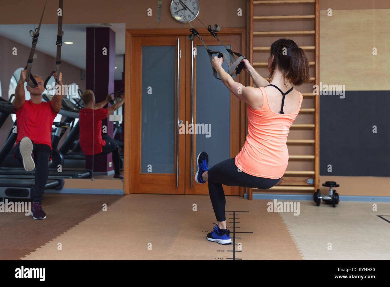 Fitness partners, sports people are working out with TRX in gym. Total body resistance exercises Stock Photo