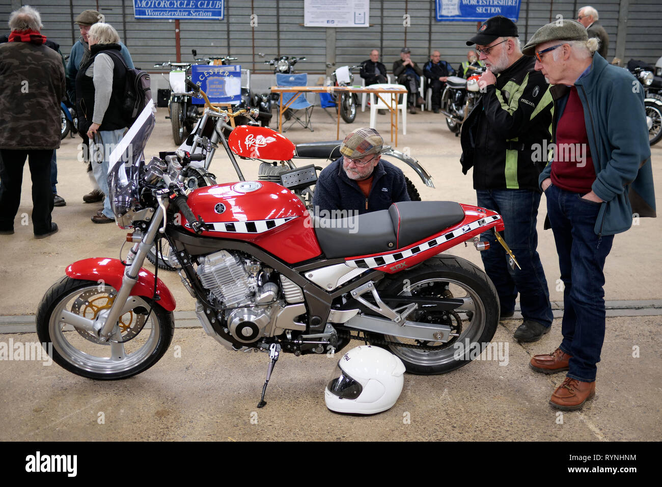 Bike enthusiasts looking at a 1980's red Yamaha SRX600 at a classic vehicle show at Three Counties Showground, Malvern, England, UK Stock Photo