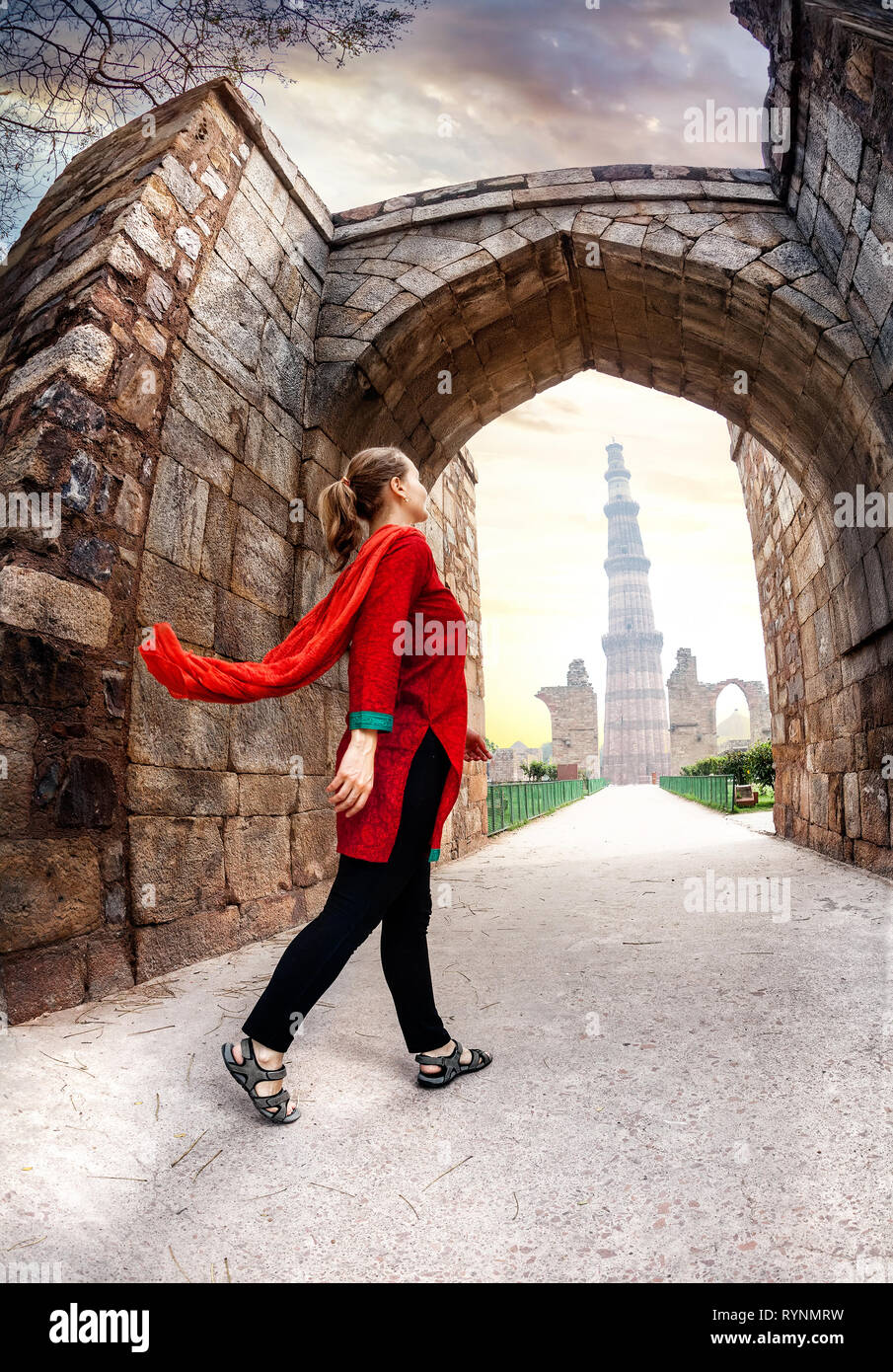 Woman in red costume going to Qutub Minar tower in Delhi, India Stock Photo