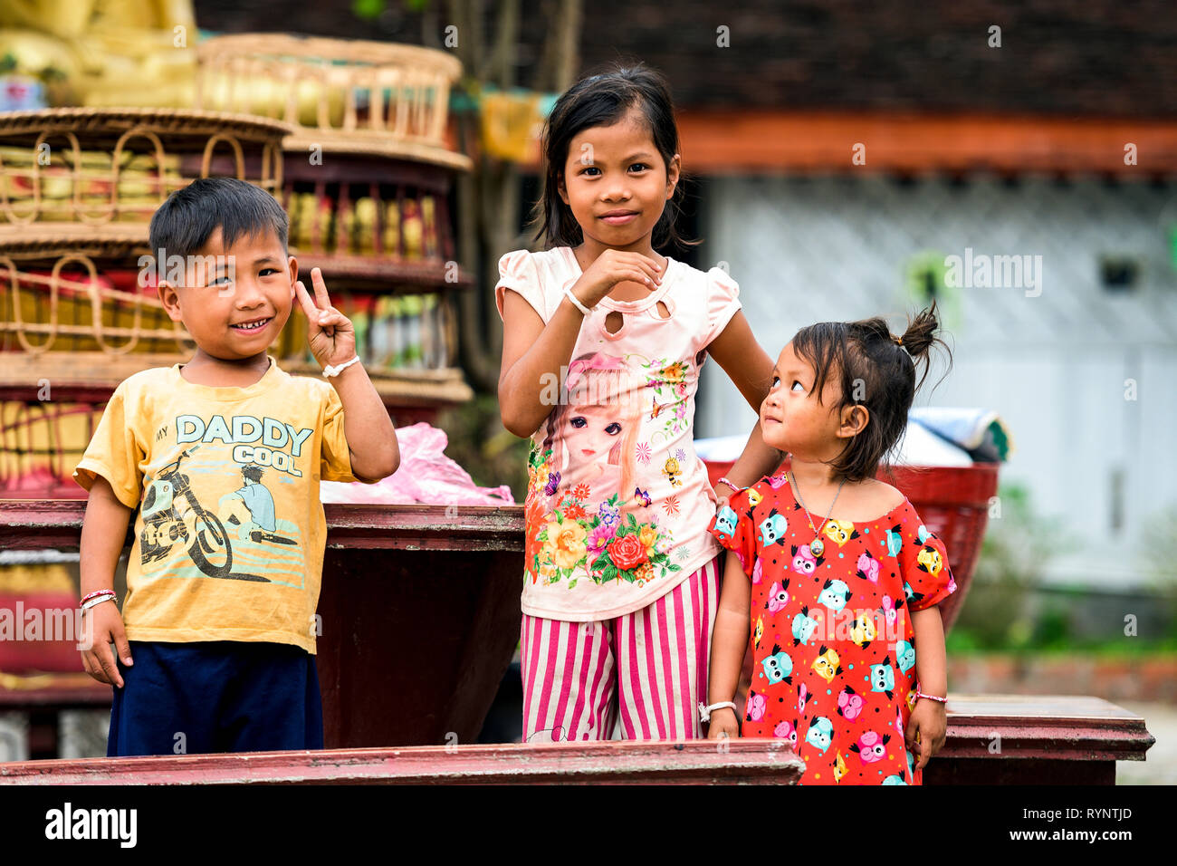 Portraits of three beautiful Laotian children who smile and have fun in a temple in Luang Prabang, Laos. Stock Photo