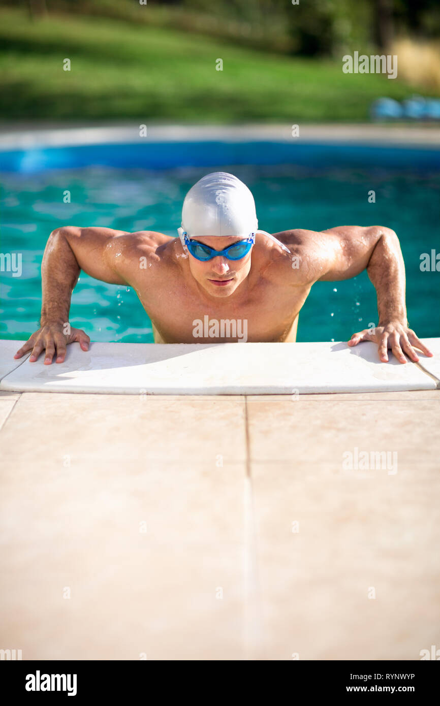 Muscular swimming man with goggles and cap in swimming pool Stock Photo