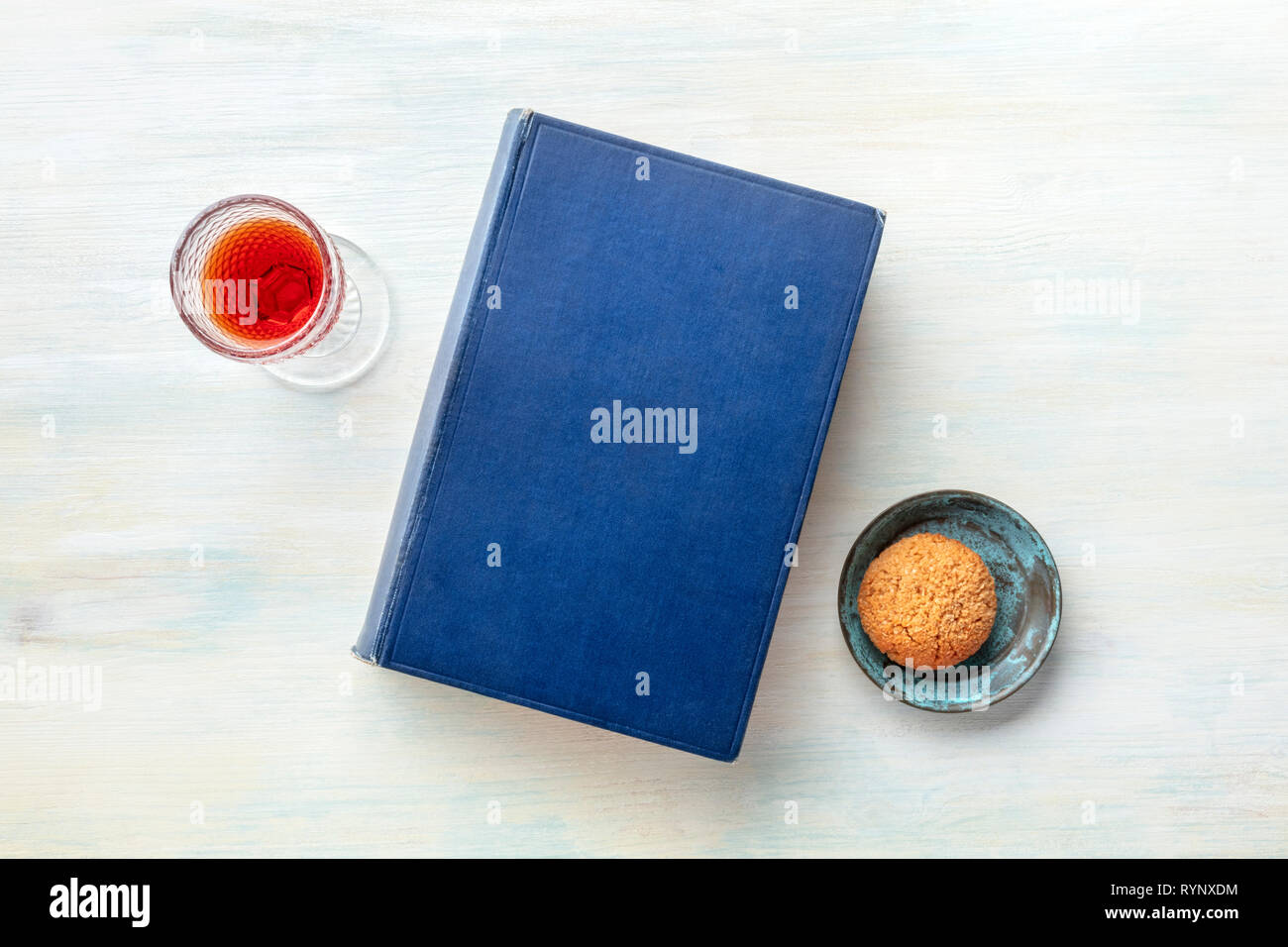 An old book with a glass of dessert wine and a biscuit, shot from above with a place for text Stock Photo