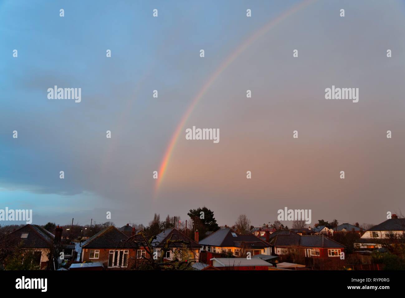 A winter rainbow against a dark stormy sky in suburban area Shepperton England UK Stock Photo
