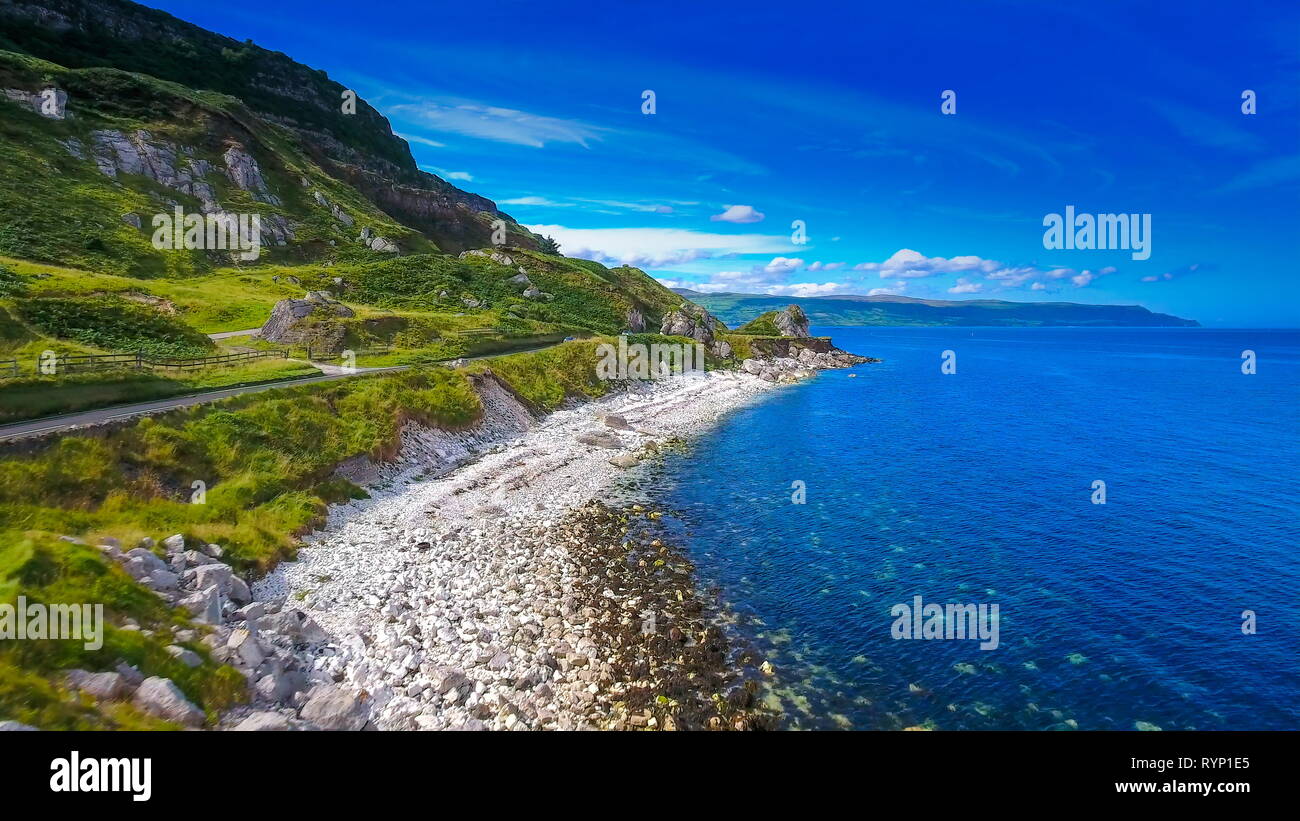 The long road and the coastal shore in Cushendun the long road on the side of the mountain facing the big blue sea in this small village in North Irel Stock Photo