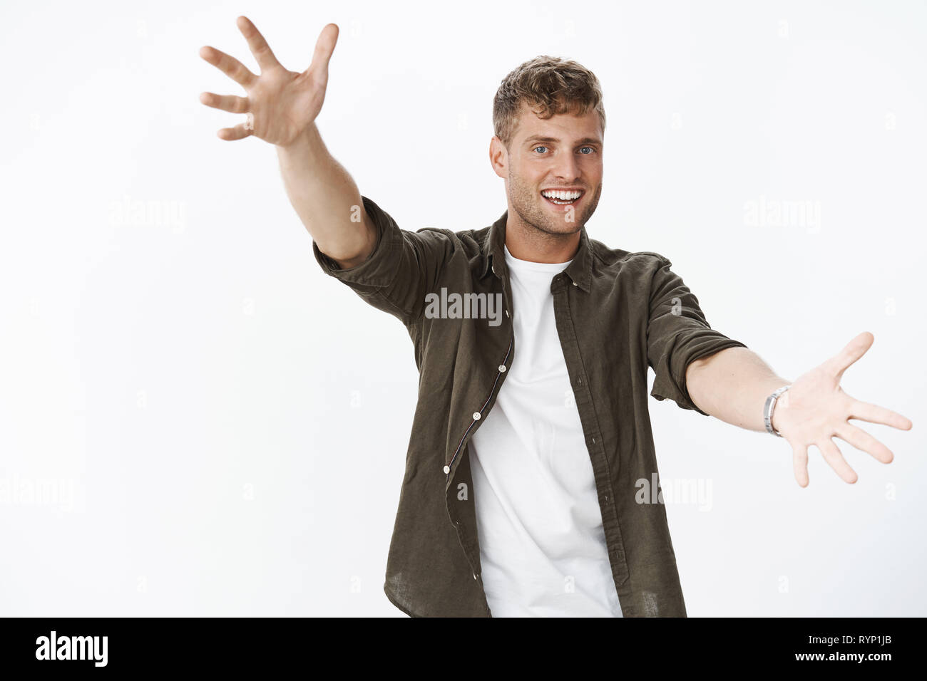 Jazz hands make day brighter. Joyful and carefree charming male with bristle, blue eyes, fair hair extending arms towards camera to give warm friendly Stock Photo