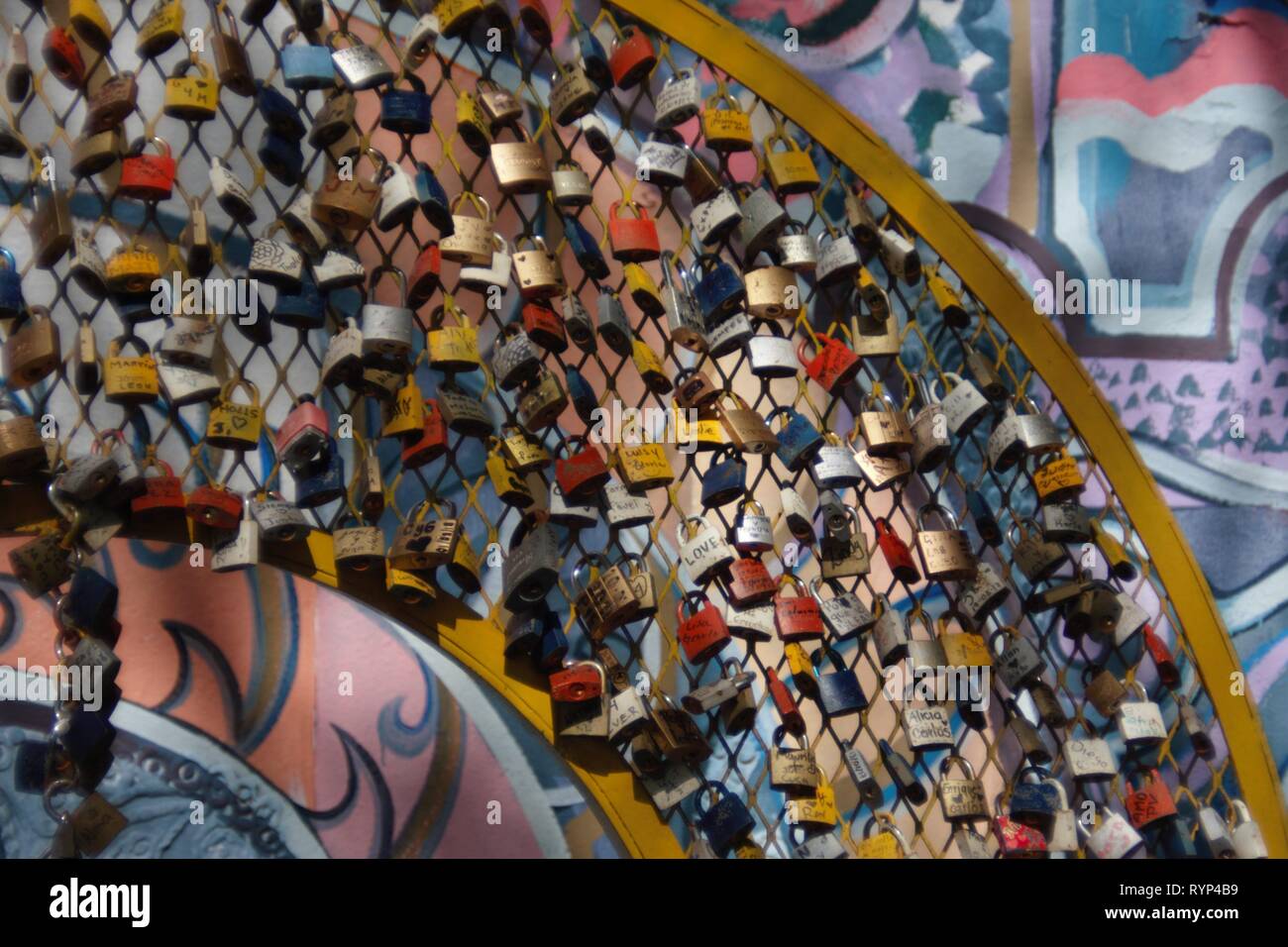 Urban modern Art piece made of personalized locks with painting behind it. Many of the locks contain the name of couples that demonstrate their love. Stock Photo