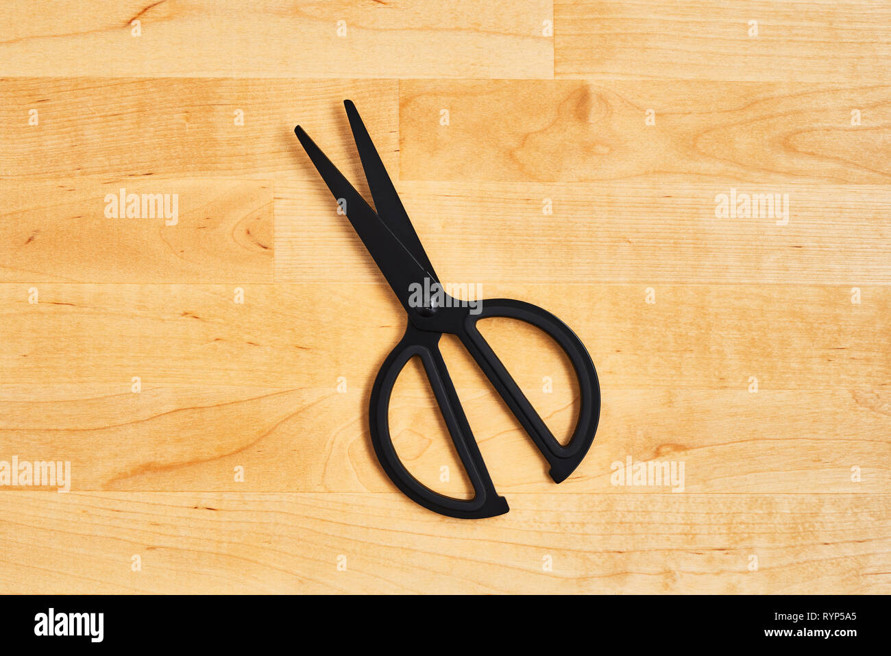 Black scissors on yellow wooden table. Top view. Copy space for text or design. Stock Photo