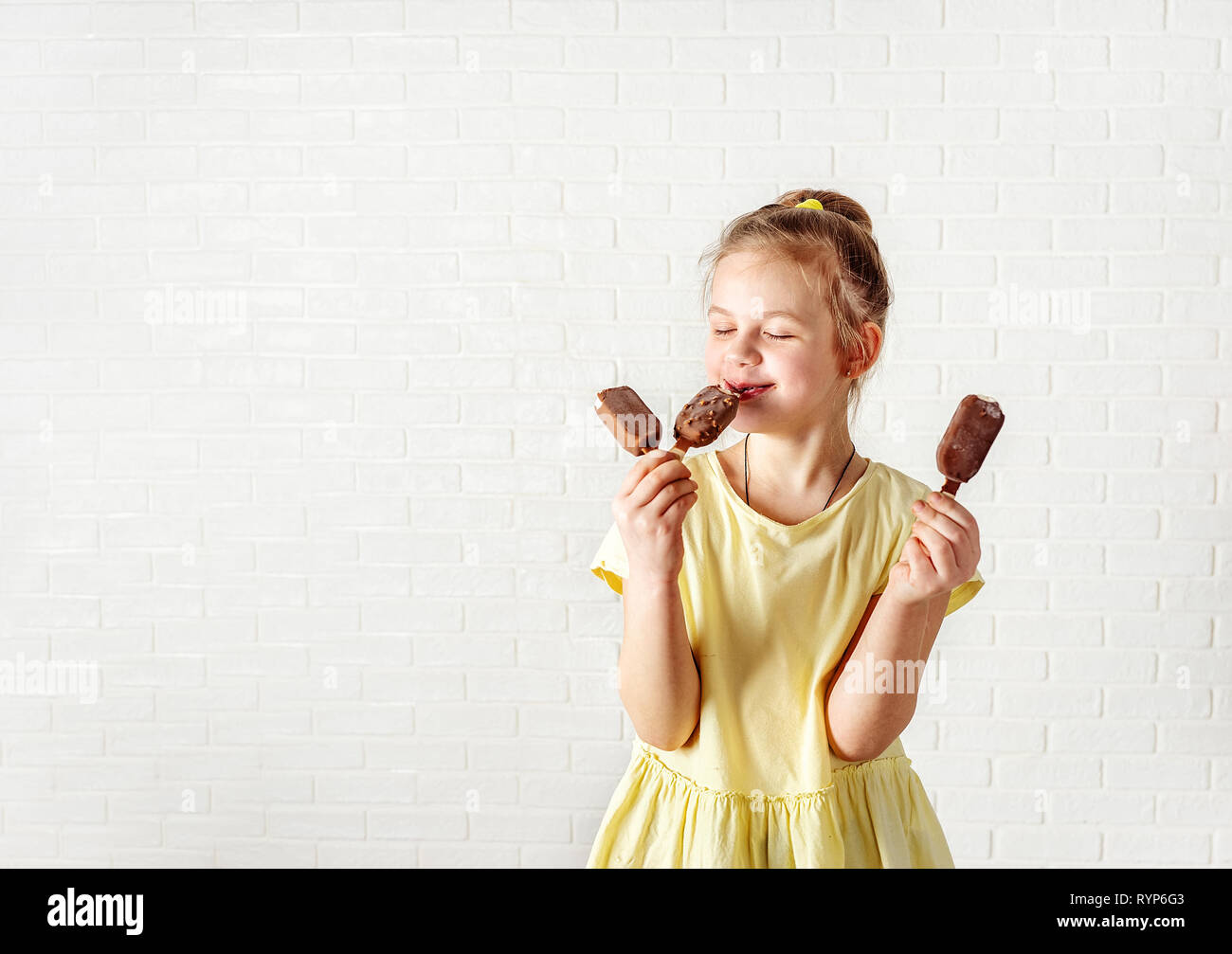 Happy little girl eating chocolate ice cream popsicle at summer time Stock Photo