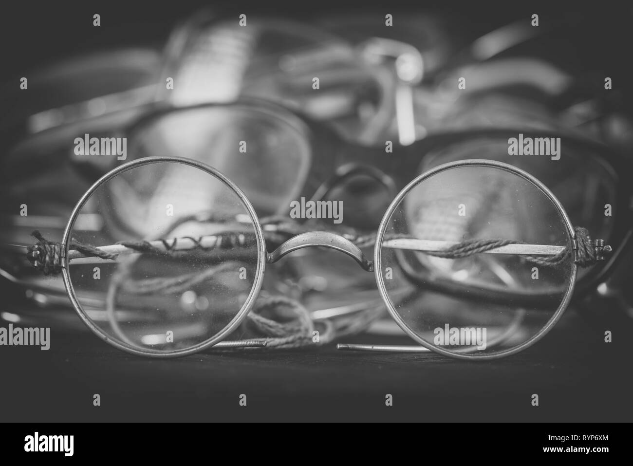 Heap of scratched and broken eyeglasses on black wooden boards. Repairing and replacing old eyeglasses, eye care Stock Photo