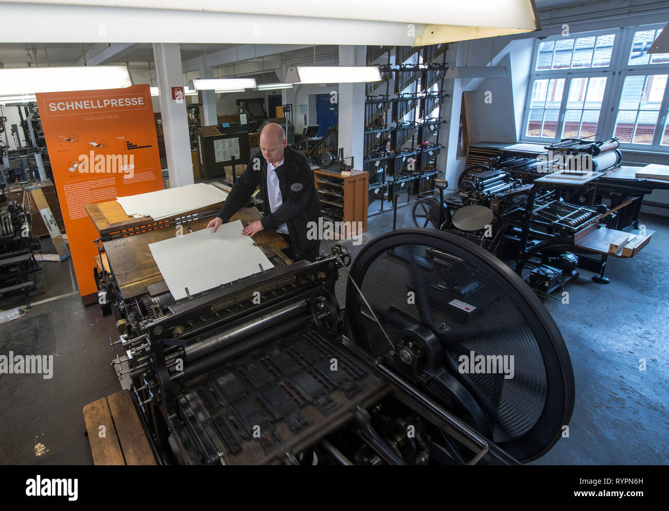 14 March 2019, Saxony, Leipzig: Thomas Kurz, typesetter and employee of the Museum für Druckkunst Leipzig, prints on a letterpress from 1906. The rooms of the historic printing workshop breathe 500 years of printing history with about 100 functioning machines and presses for historical casting, typesetting and printing techniques. On Friday (15.03.2019), the museum will participate in the first nationwide Print Art Day and offer a colourful programme. On 15 March last year, the artistic printing techniques were included in the German Unesco Commission's nationwide list of Intangible Cultural H Stock Photo