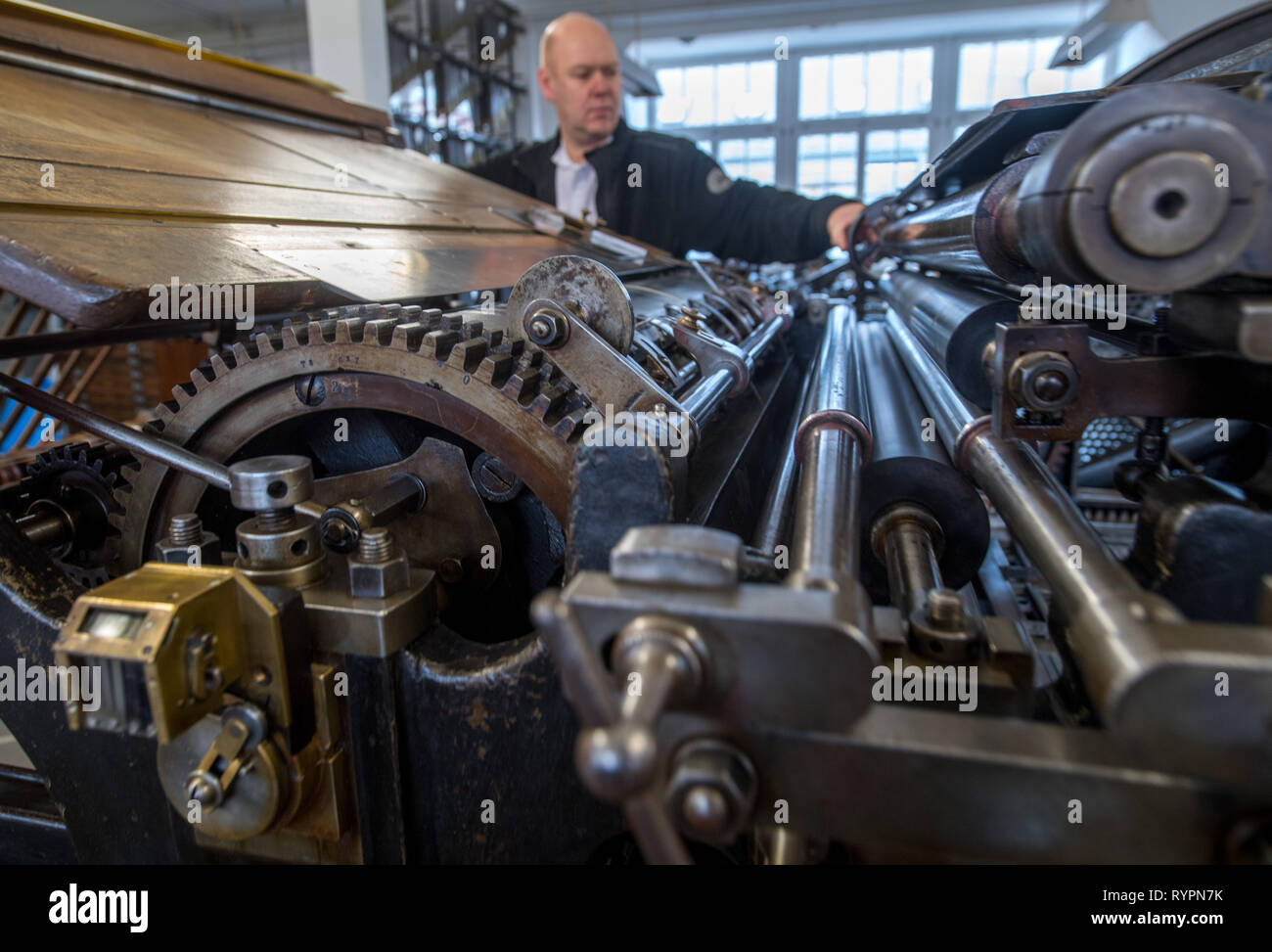 14 March 2019, Saxony, Leipzig: Thomas Kurz, typesetter and employee of the Museum für Druckkunst Leipzig, prints on a letterpress from 1906. The rooms of the historic printing workshop breathe 500 years of printing history with about 100 functioning machines and presses for historical casting, typesetting and printing techniques. On Friday (15.03.2019), the museum will participate in the first nationwide Print Art Day and offer a colourful programme. On 15 March last year, the artistic printing techniques were included in the German Unesco Commission's nationwide list of Intangible Cultural H Stock Photo