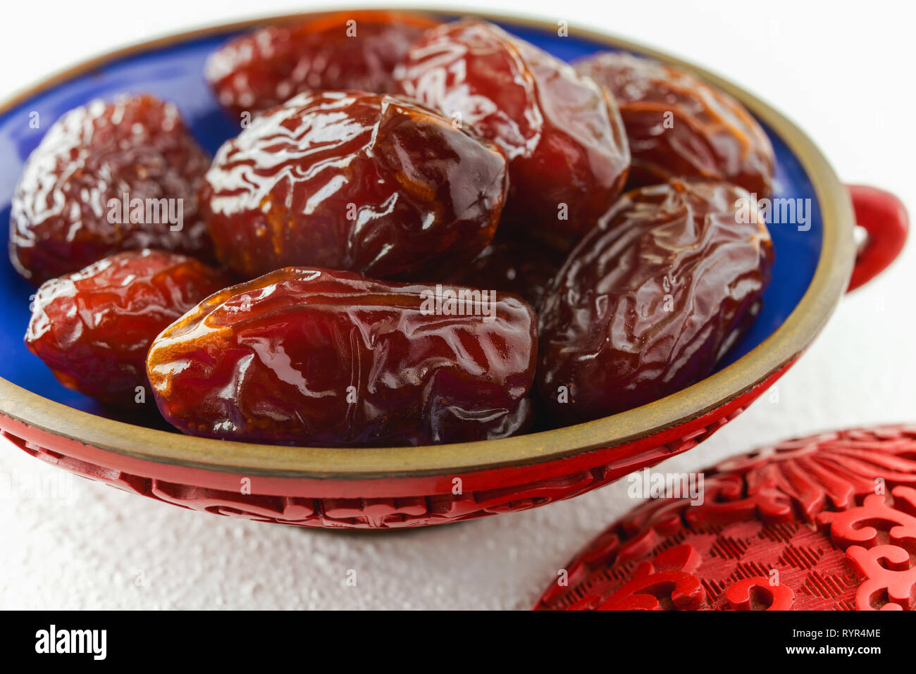 Dates in a bowl, close up on a kitchen table with white background Stock Photo