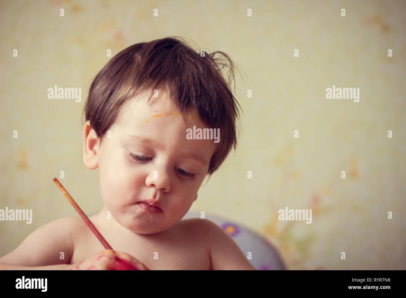 The boy paints on paper. Red and yellow paint. Children's activities. Children's hobby. Drawing Stock Photo
