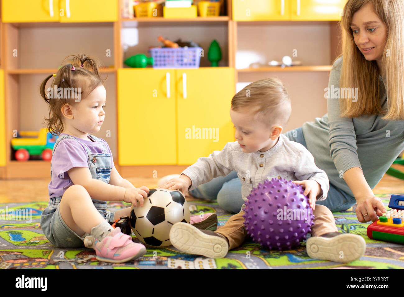little children girl and boy playing with balls in nursery Stock Photo