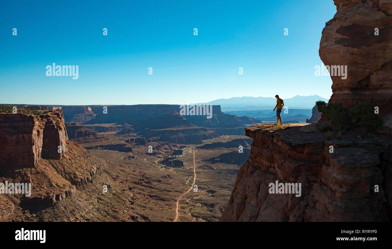Young man standing at the edge of a fur cliff over Shafer Canyon Road, Shafer Canyon Overlook, Island in the Sky Stock Photo