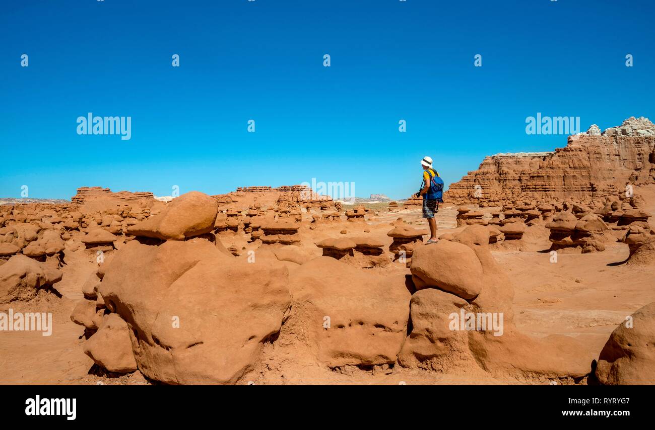 Tourist, young man likes Hodoo, eroded Hoodoos, rock formation of Entrada sandstone, Goblin Valley State Park, San Rafael Reef Stock Photo