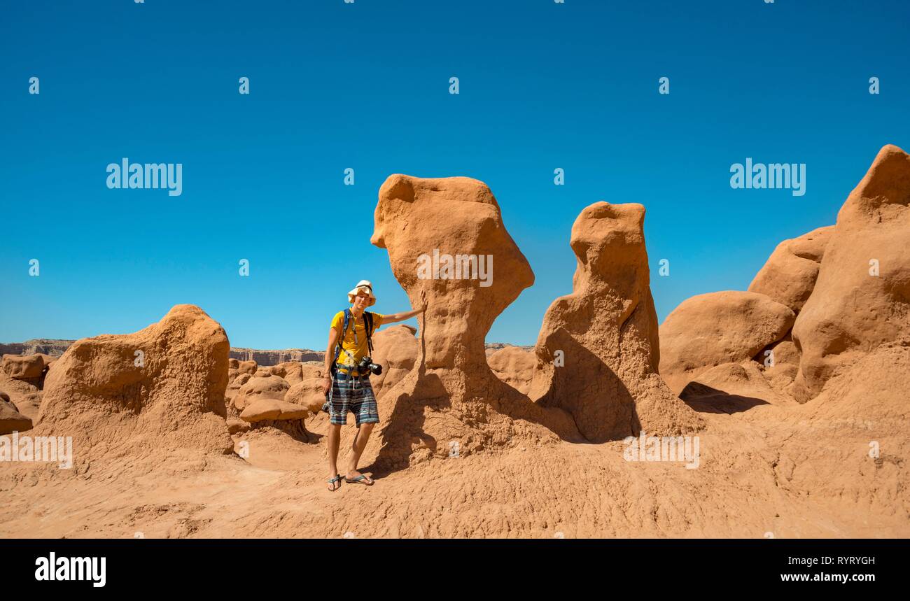 Tourist, young man next to eroded Hoodoos, rock formation of Entrada sandstone, Goblin Valley State Park, San Rafael Reef, Utah Stock Photo