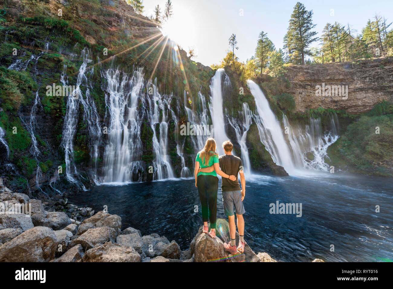 Young couple standing at a waterfall, McArthur-Burney Falls Memorial State Park, California, USA Stock Photo