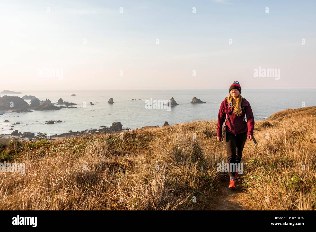 Young woman on a hiking trail along the rugged coast with many rocks, Whaleshead, Samuel H. Boardman State Scenic Corridor Stock Photo