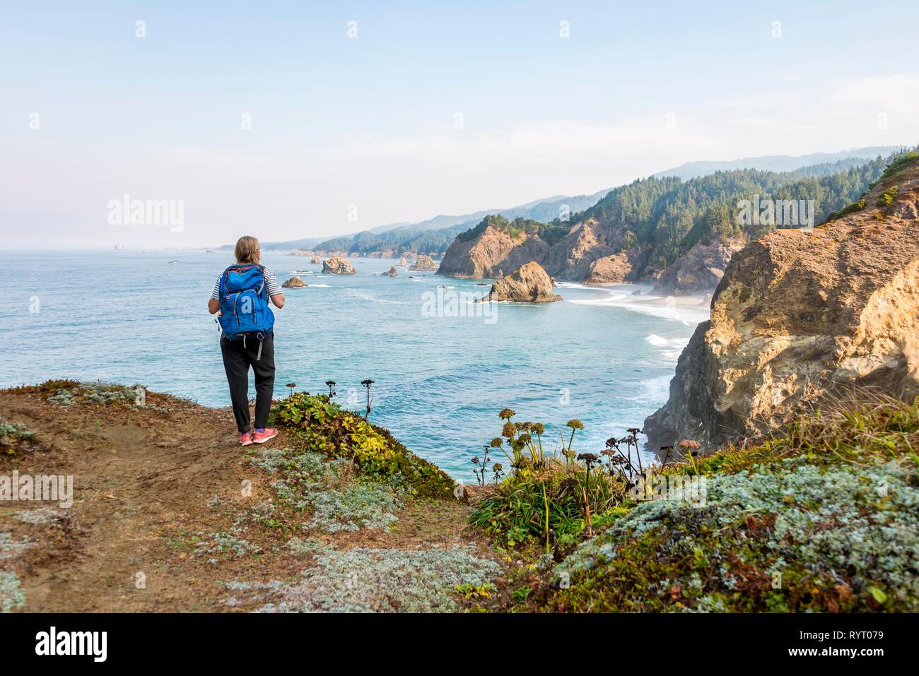 Young woman looking out to sea, rugged rocky coast, Samuel H. Boardman State Scenic Corridor, Indian Sands Trail, Oregon, USA Stock Photo
