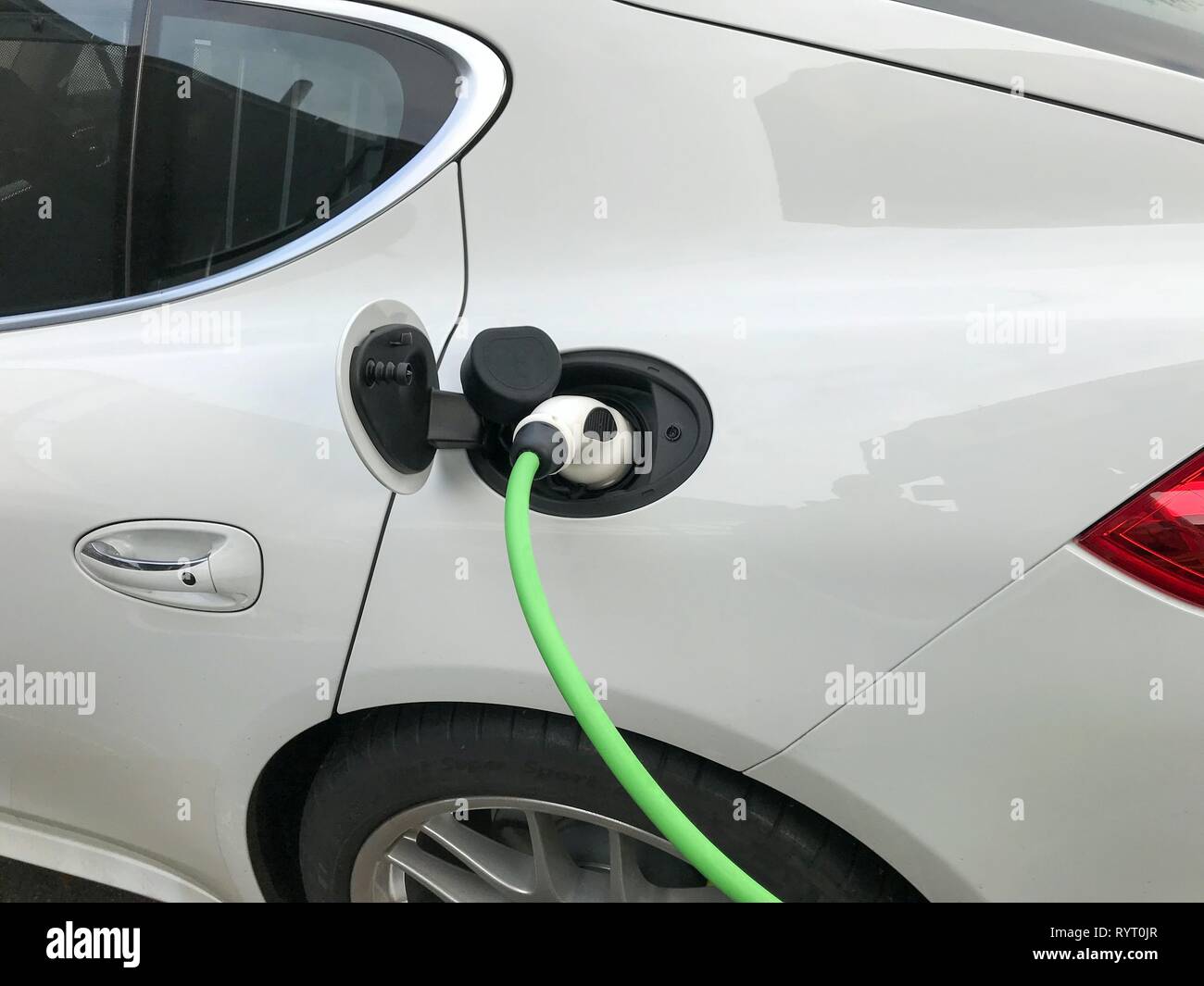 Charging plug on electric car, car being charged at charging station