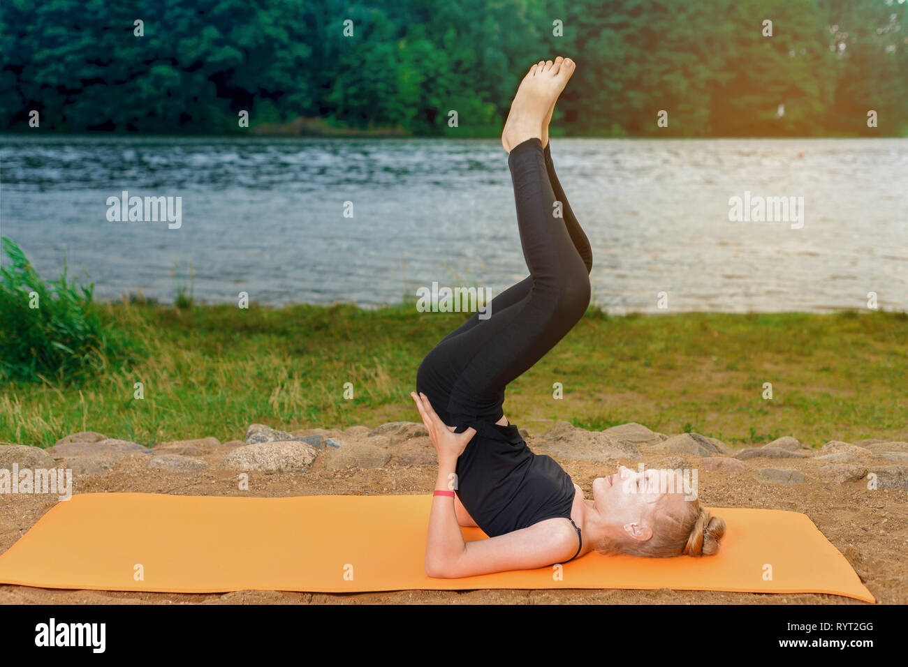 Blonde girl in yoga pants Little Girl Blonde In Leggings And T Shir Is Engaged In Yoga Pilates On The River Bank At Sunset On An Orange Mat Stock Photo Alamy