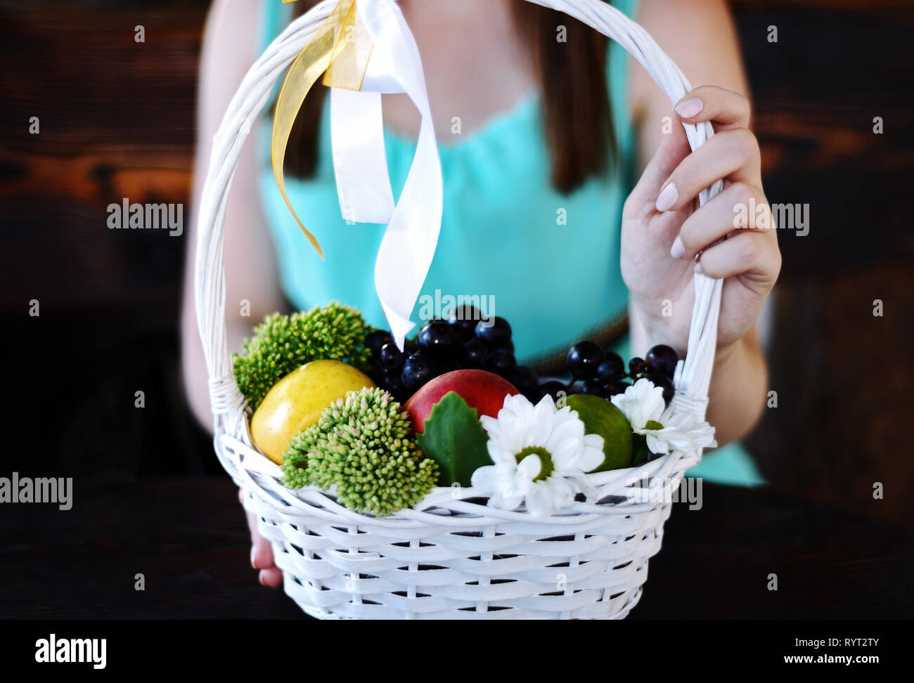 beautiful girl in a blue dress is holding a basket with fruits and ...