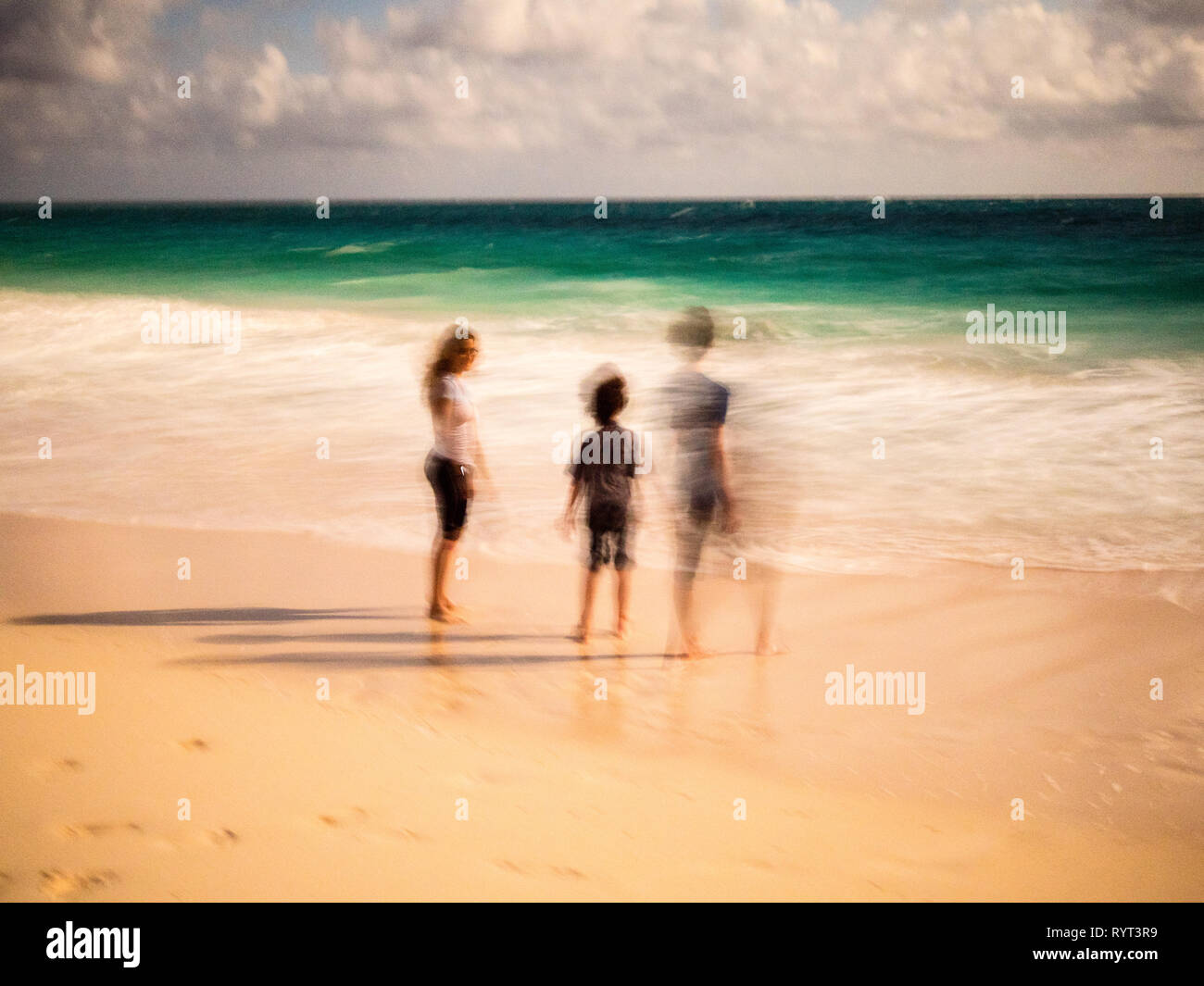 Three Young people on beach, Tropical Beach Nigh time, Moonlight, Governors Harbour, Eleuthera, The Bahamas, The Caribbean. Stock Photo