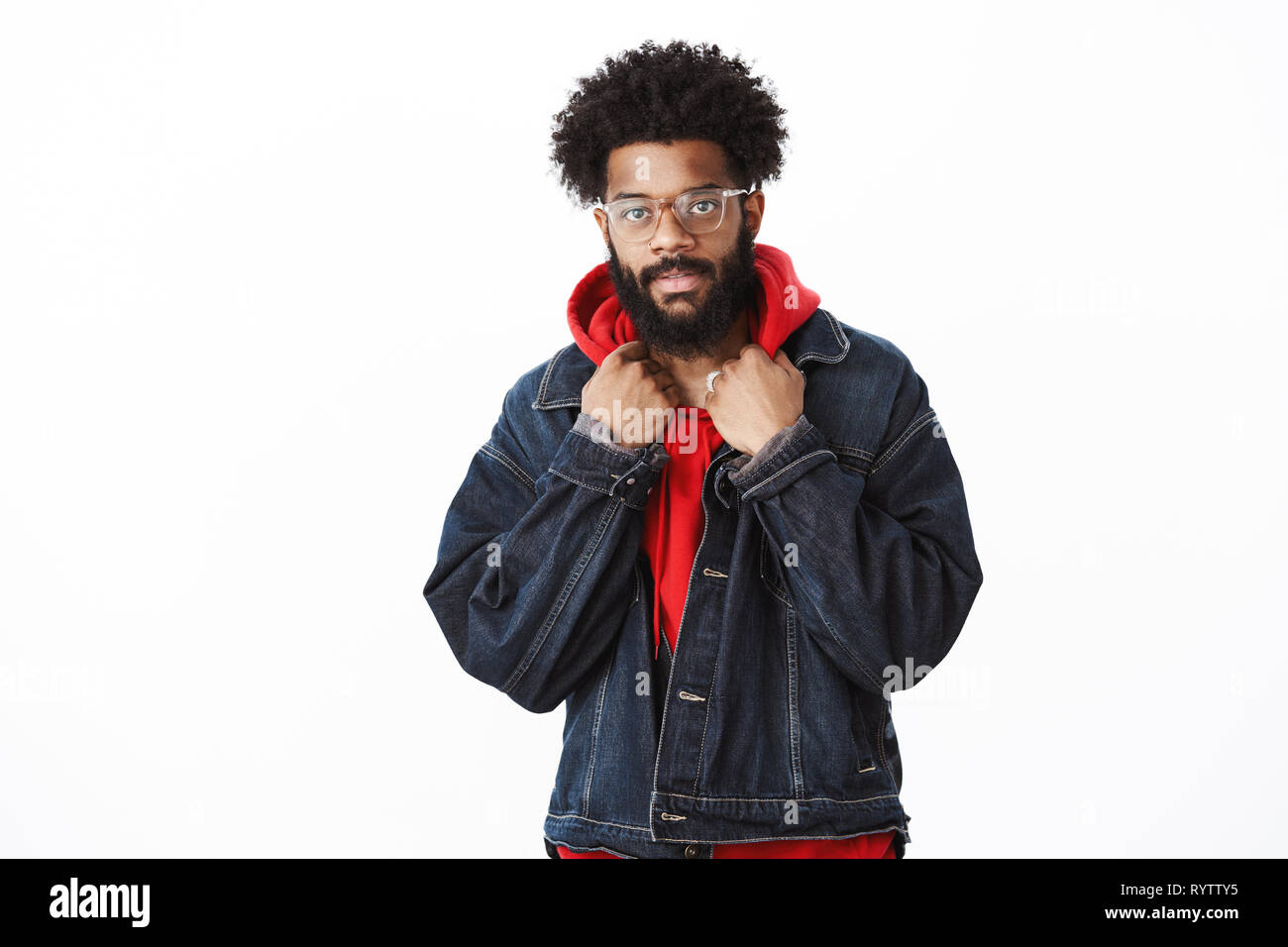 Guy checking outfit in mirror looking lit and stylish smiling at camera self-assured as getting ready to date standing in denim jacket touching collar Stock Photo