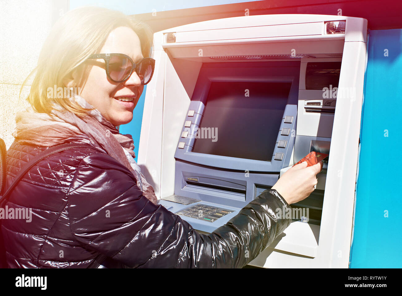 Woman with a bank card at an ATM Stock Photo