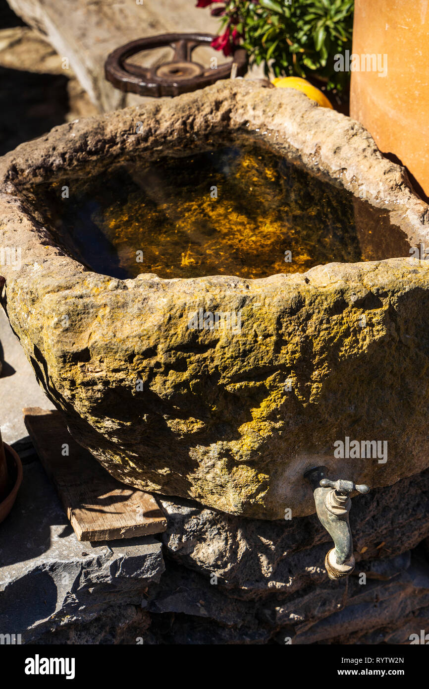 Water trough carved from stone with a tap in a garden in Las Fuentes, Guia de Isora, Tenerife, Canary Islands, Spain Stock Photo