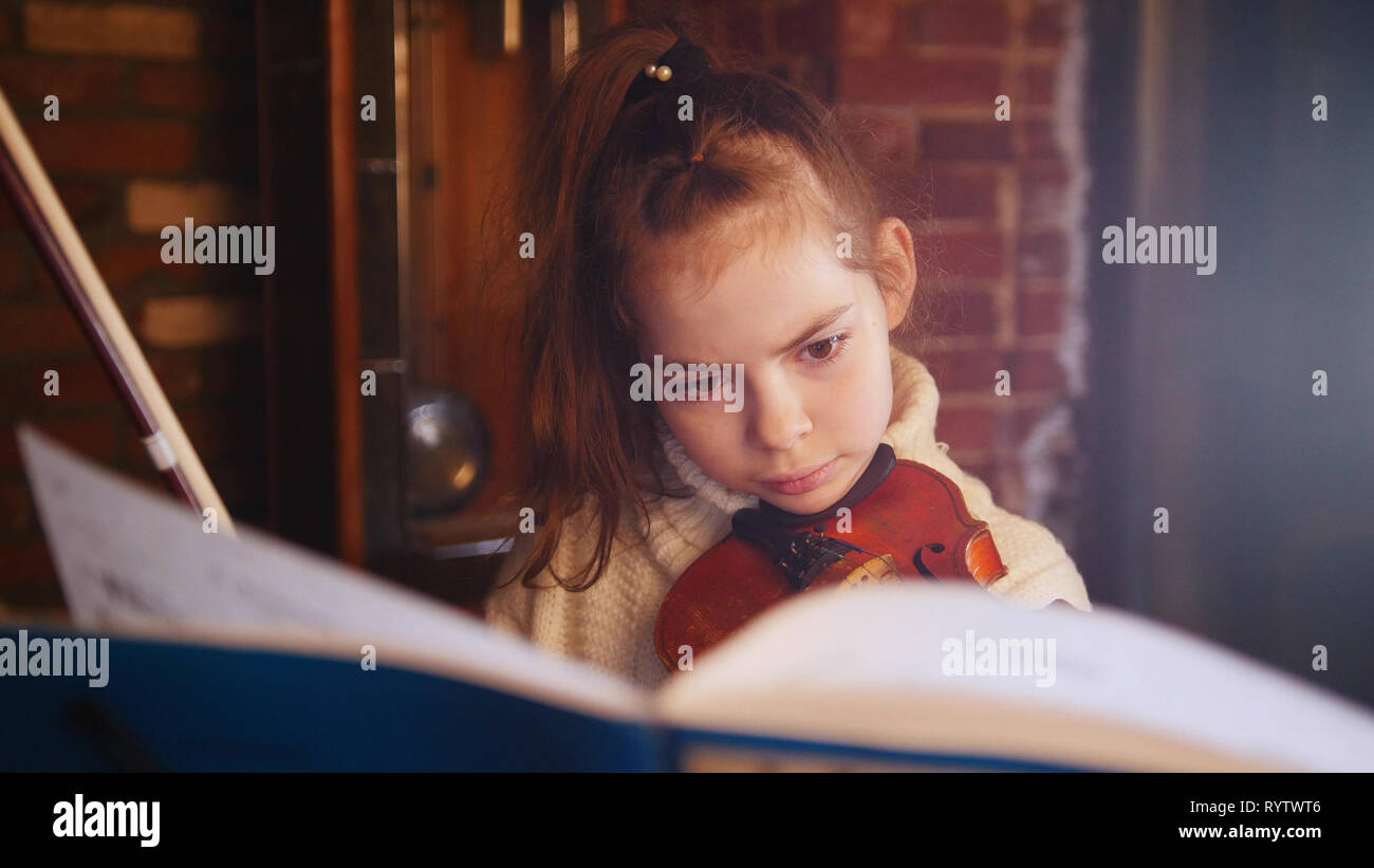 A little concentrated girl playing violin by notes Stock Photo - Alamy