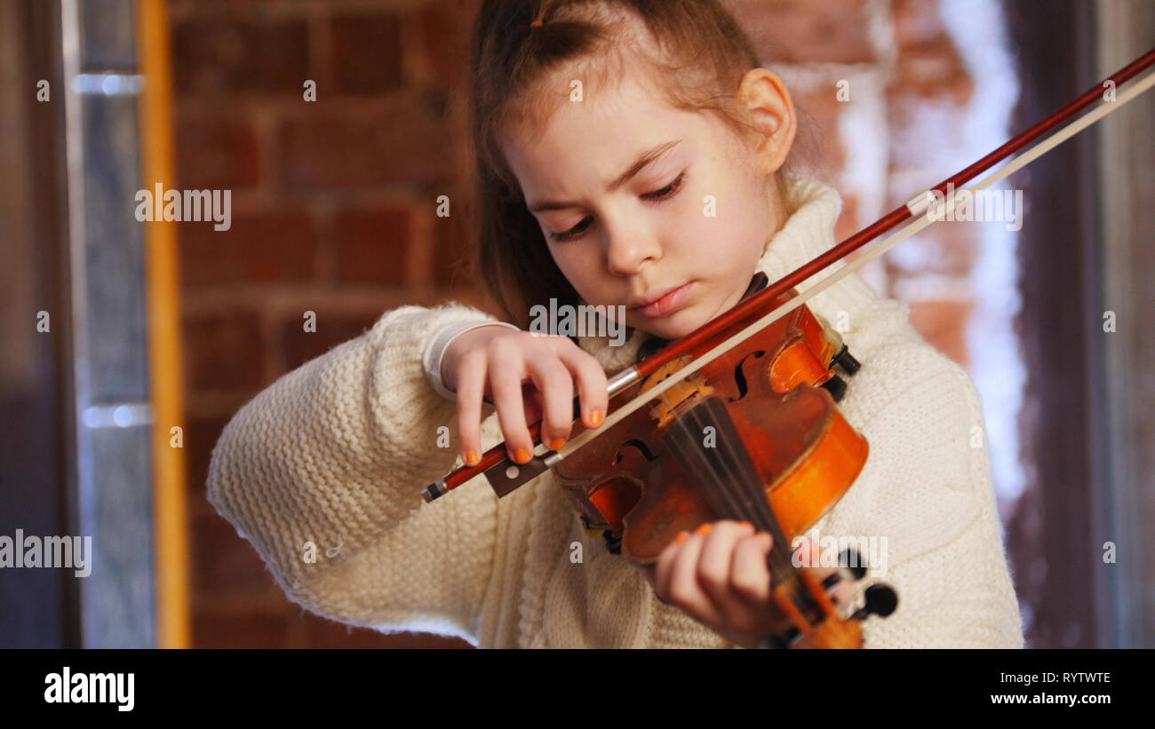 A little concentrated girl in white sweater playing violin Stock Photo ...