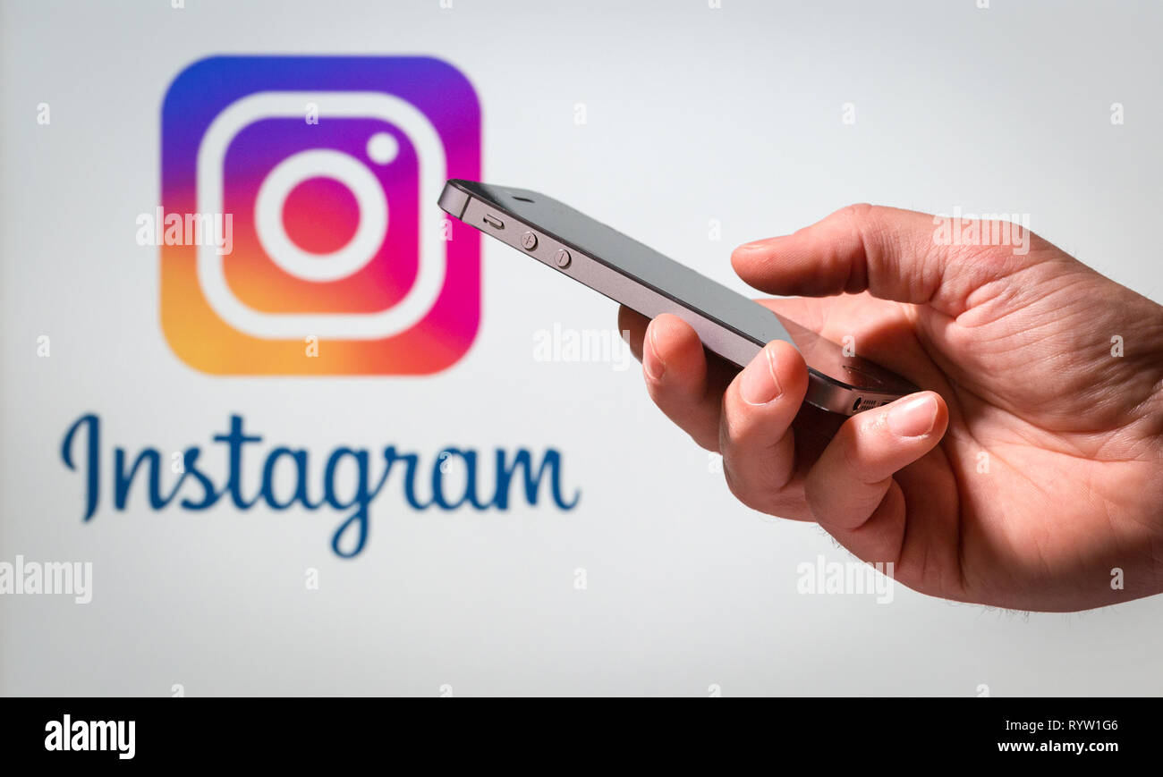 A man using his mobile phone in front of the Instagram logo Stock Photo