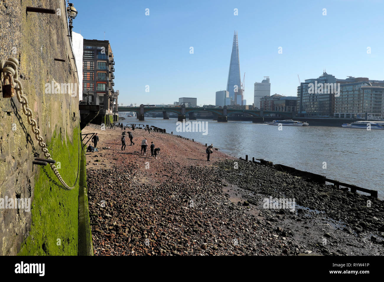 View of River Thames at low tide, Shard building, people mudlarking ...