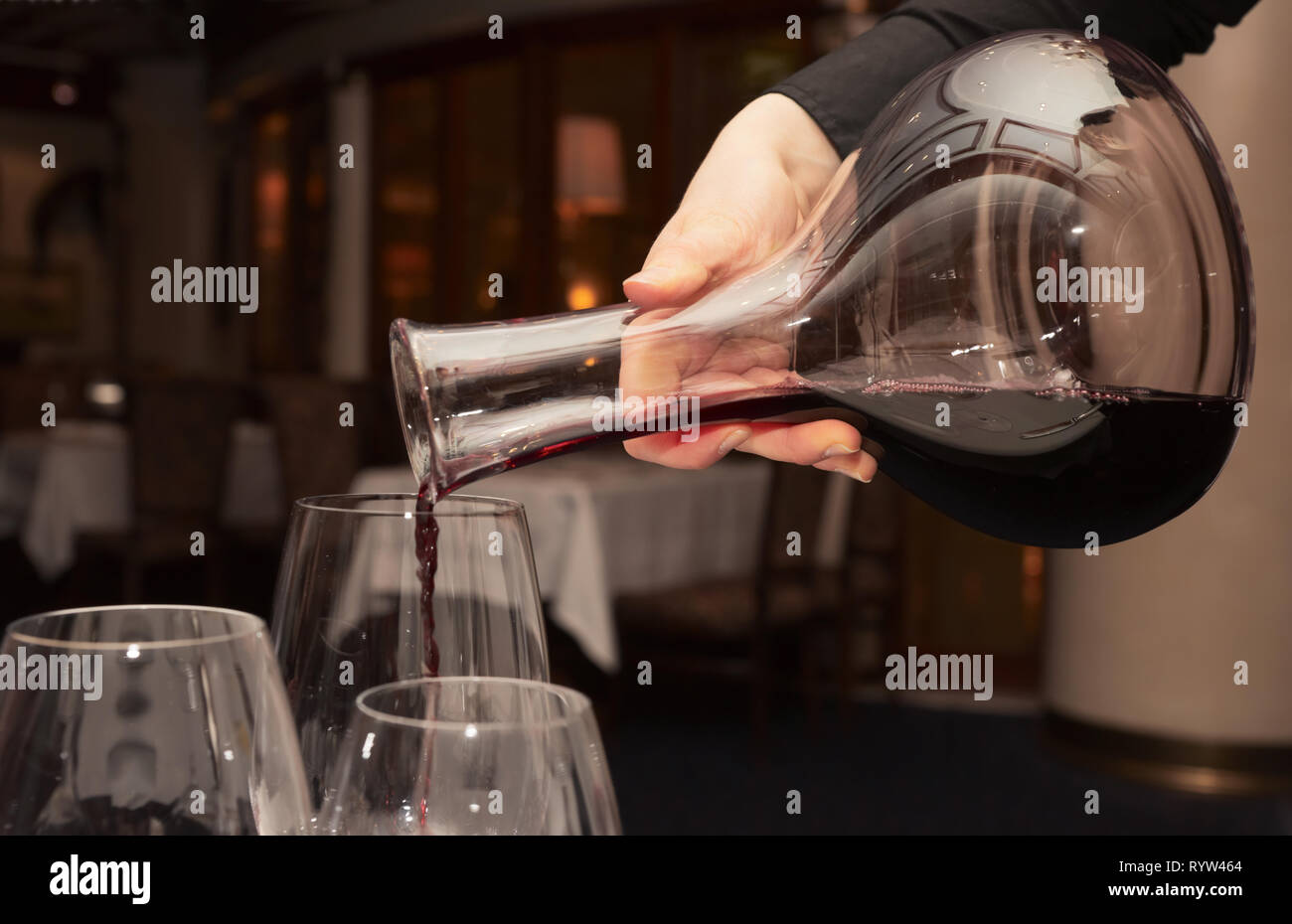 https://c8.alamy.com/comp/RYW464/waiter-pouring-red-wine-from-decanter-in-dark-restaurant-RYW464.jpg