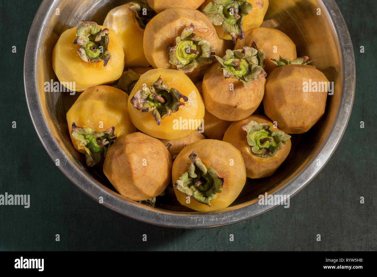 Peeled persimmons with peduncles needed to tie to them a thread for hanging and drying. Cooking dried fruits. Stock Photo