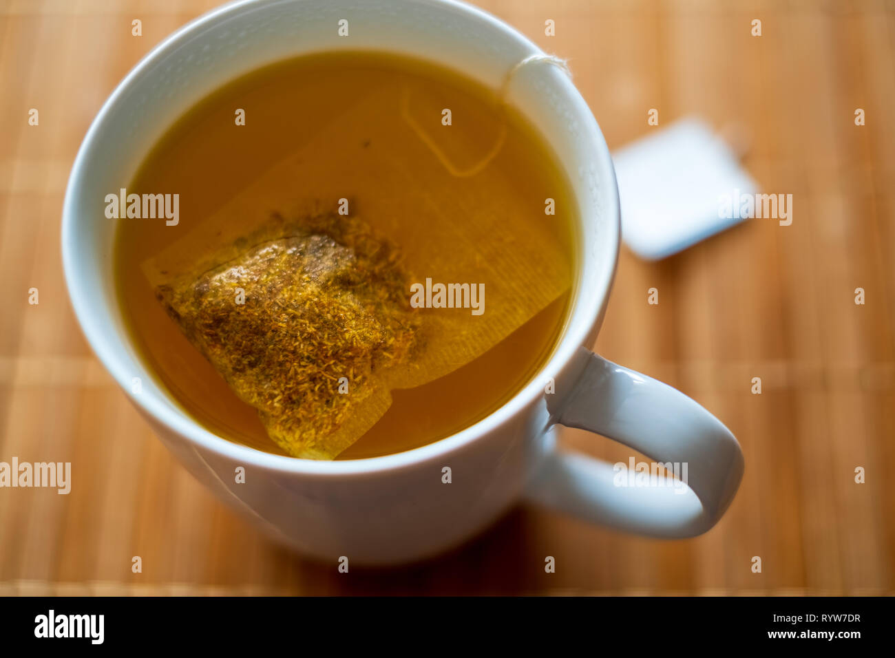 Healthy organic tea bag in hot water making tea isolated Stock Photo