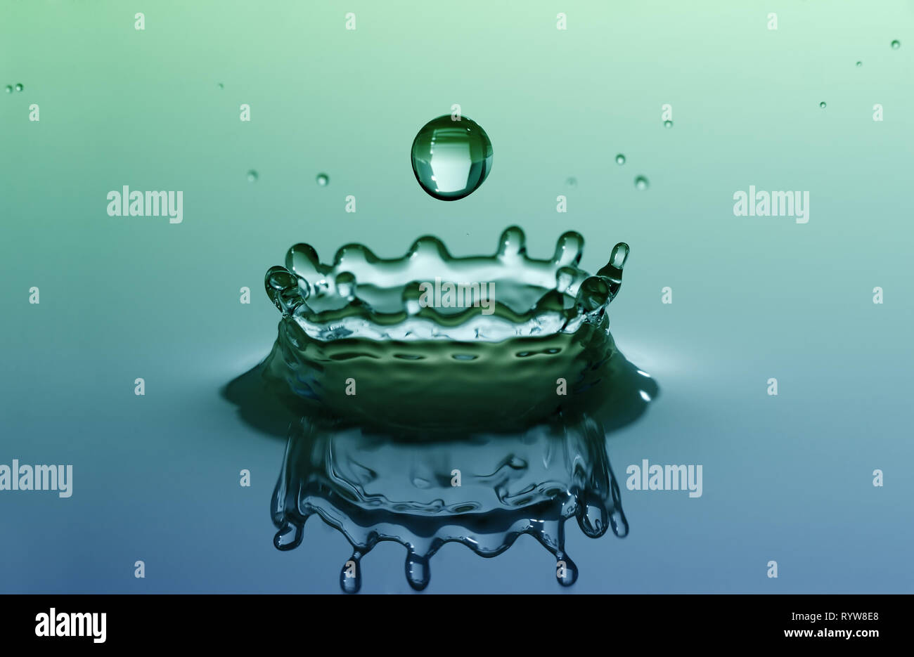 Water splash in shape of crown, with falling rain drop Stock Photo