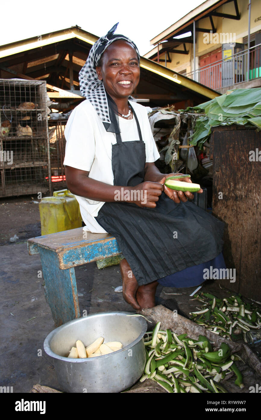 A woman food vendor peeling plantain (matooke), to cook at a food stall in Kampala, Uganda. Stock Photo