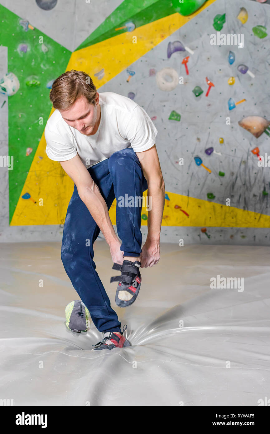 Rock climber puts on rocky shoes in a bouldering hall at a climbing gym