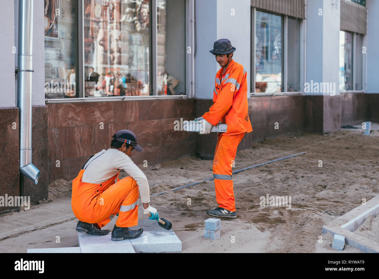 Moscow, Russia - August 14, 2015: builderworkers laid a new tile on the Pavement. Reconstruction of pavement tiles in the capital near palace Chertkov Stock Photo
