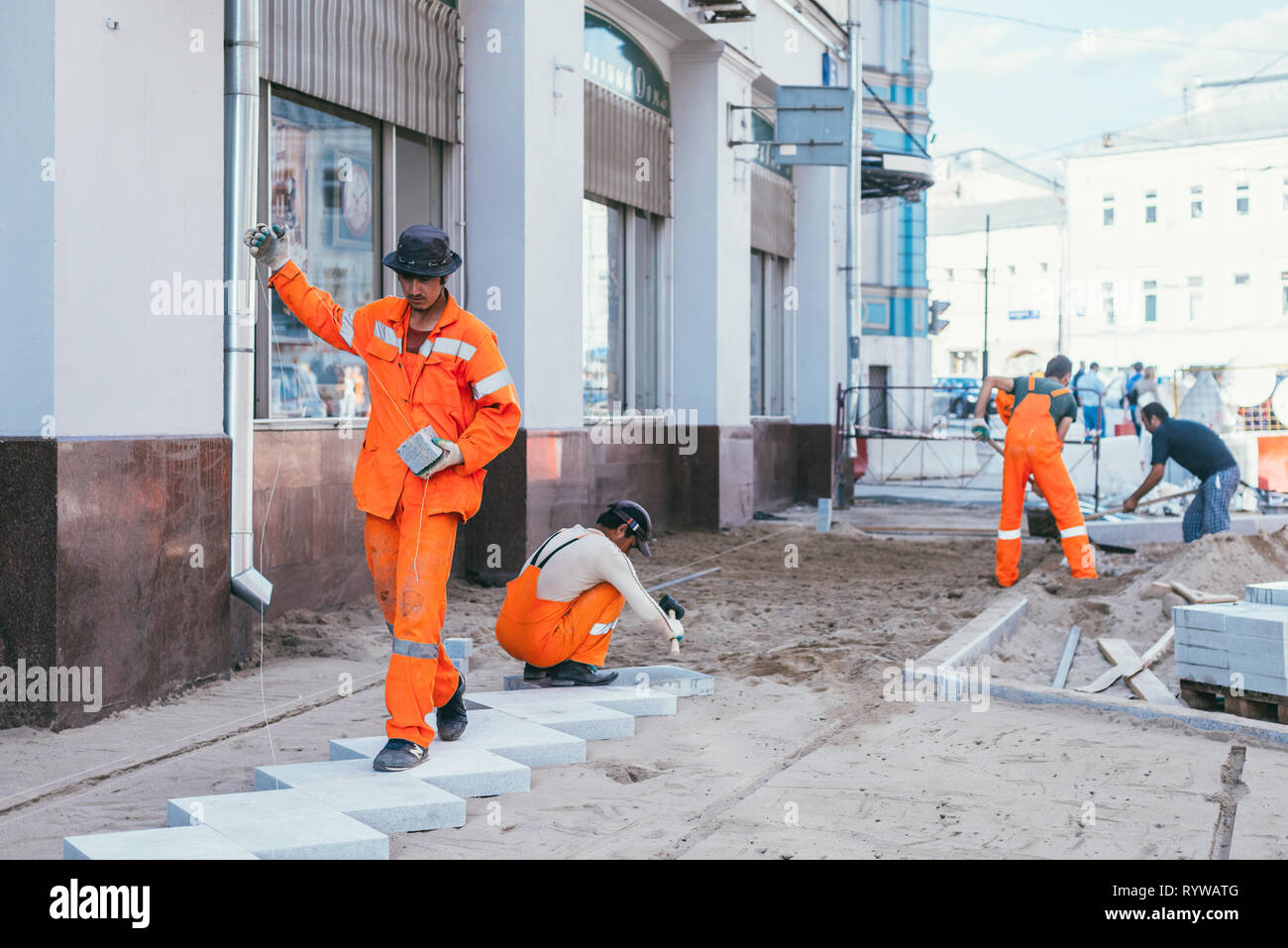 Moscow, Russia - August 14, 2015: builderworkers laid a new tile on the Pavement. Reconstruction of pavement tiles in the capital near palace Chertkov Stock Photo