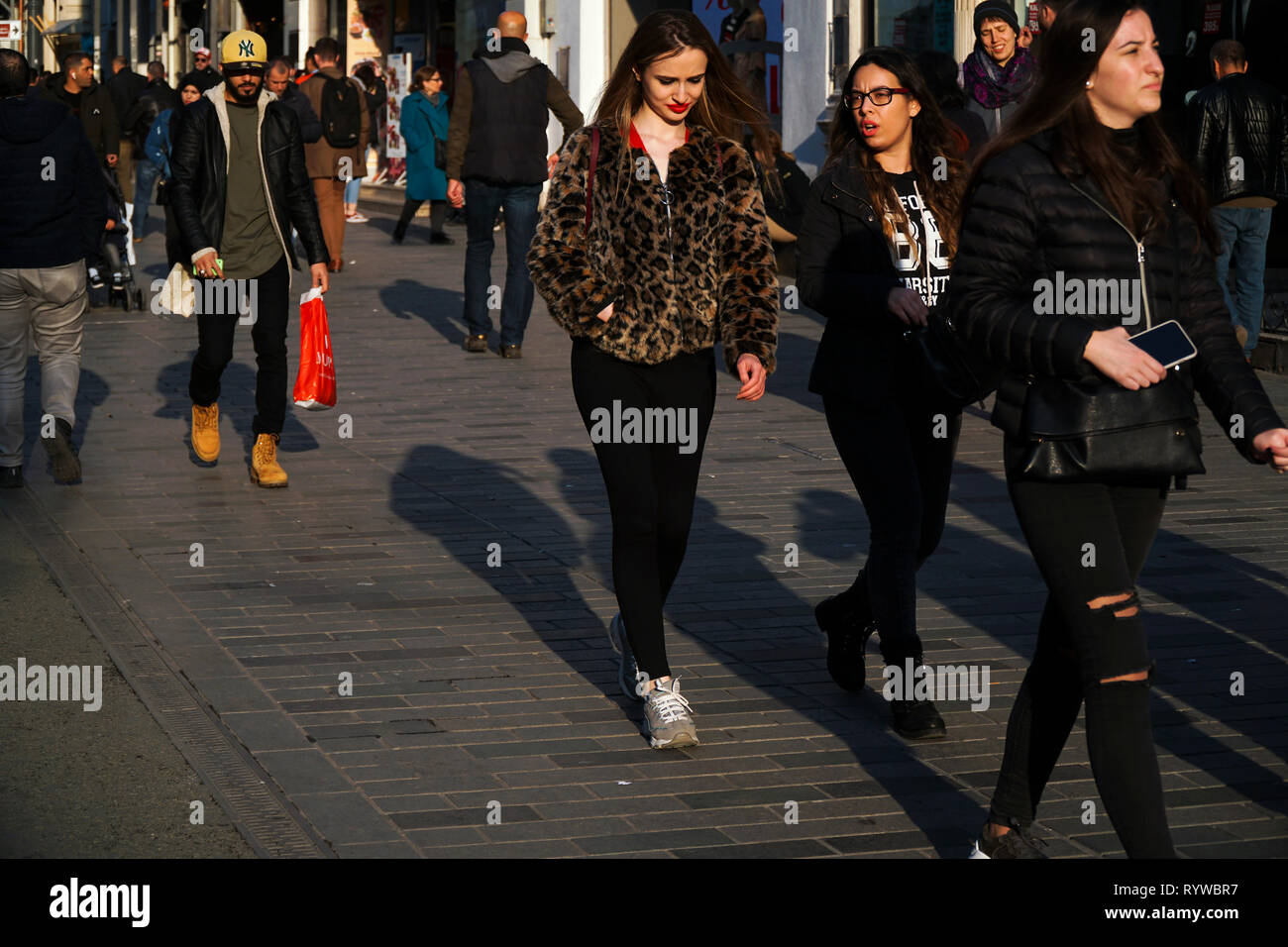 Istanbul, Turkey - March 6 , 2019 : Young women in fashionable  clothes, one of them is wearing a leopard patterned jacket and other people. Stock Photo