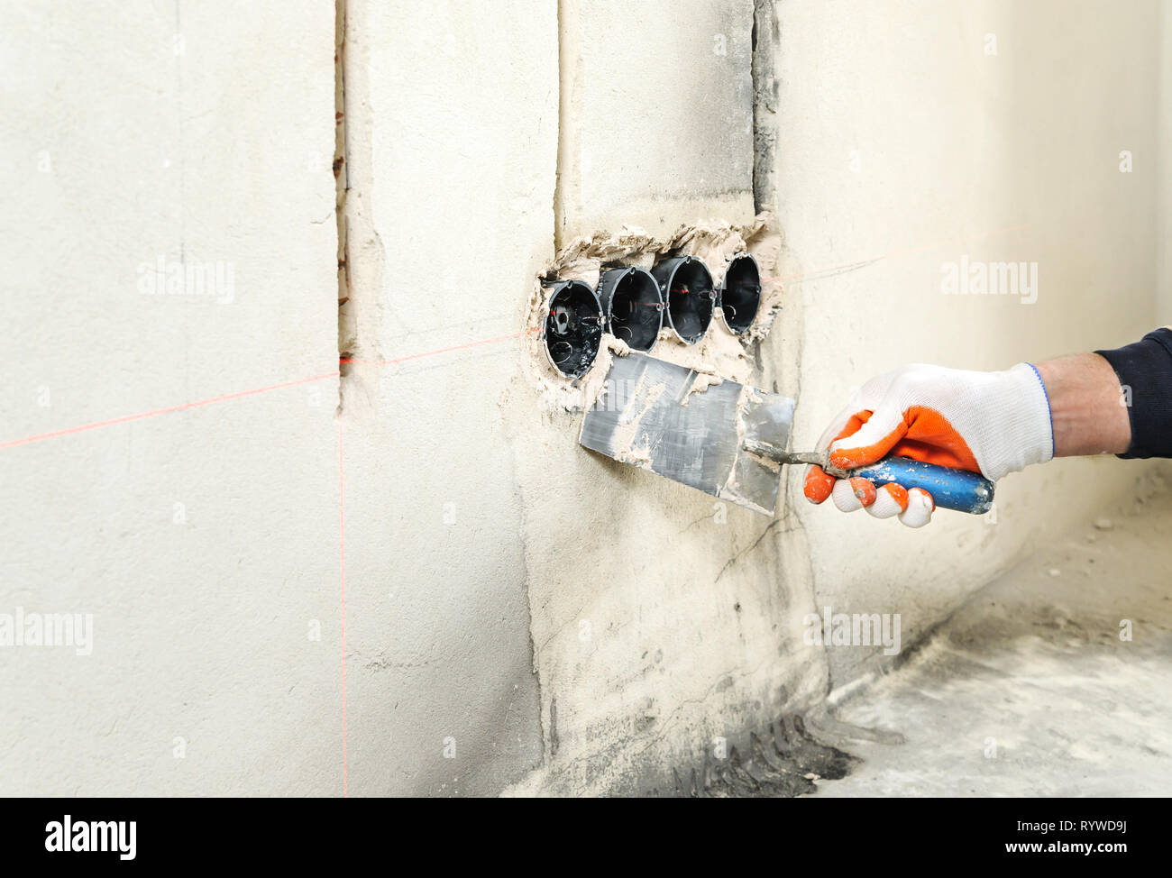 Installing electrical socket box. A worker attaches to the wall socket